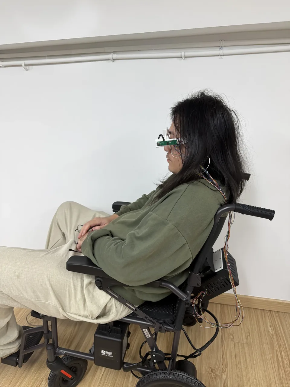 Side view of a person wearing the eye-tracking glasses while seated in the wheelchair.